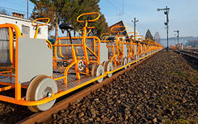 Pomarańczowe drezyny rowerowe ustawione na bocznicy kolejowej