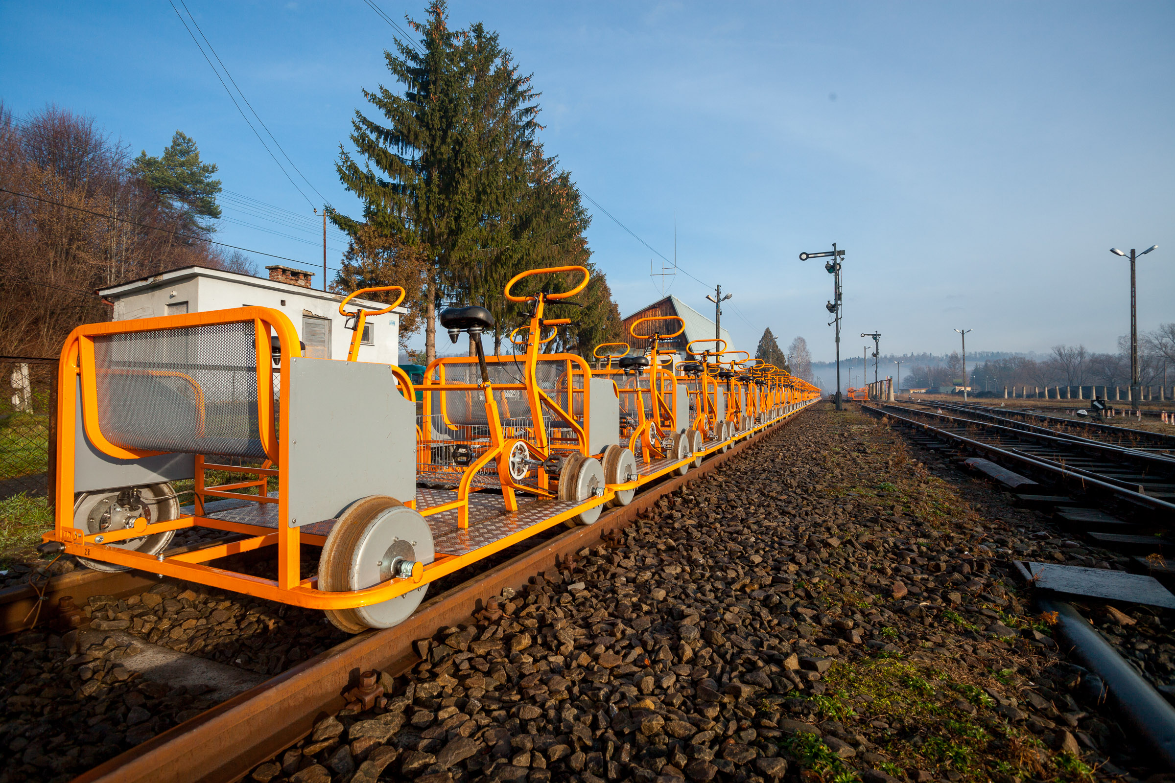 Pomarańczowe drezyny rowerowe ustawione na torach na stacji kolejowej.