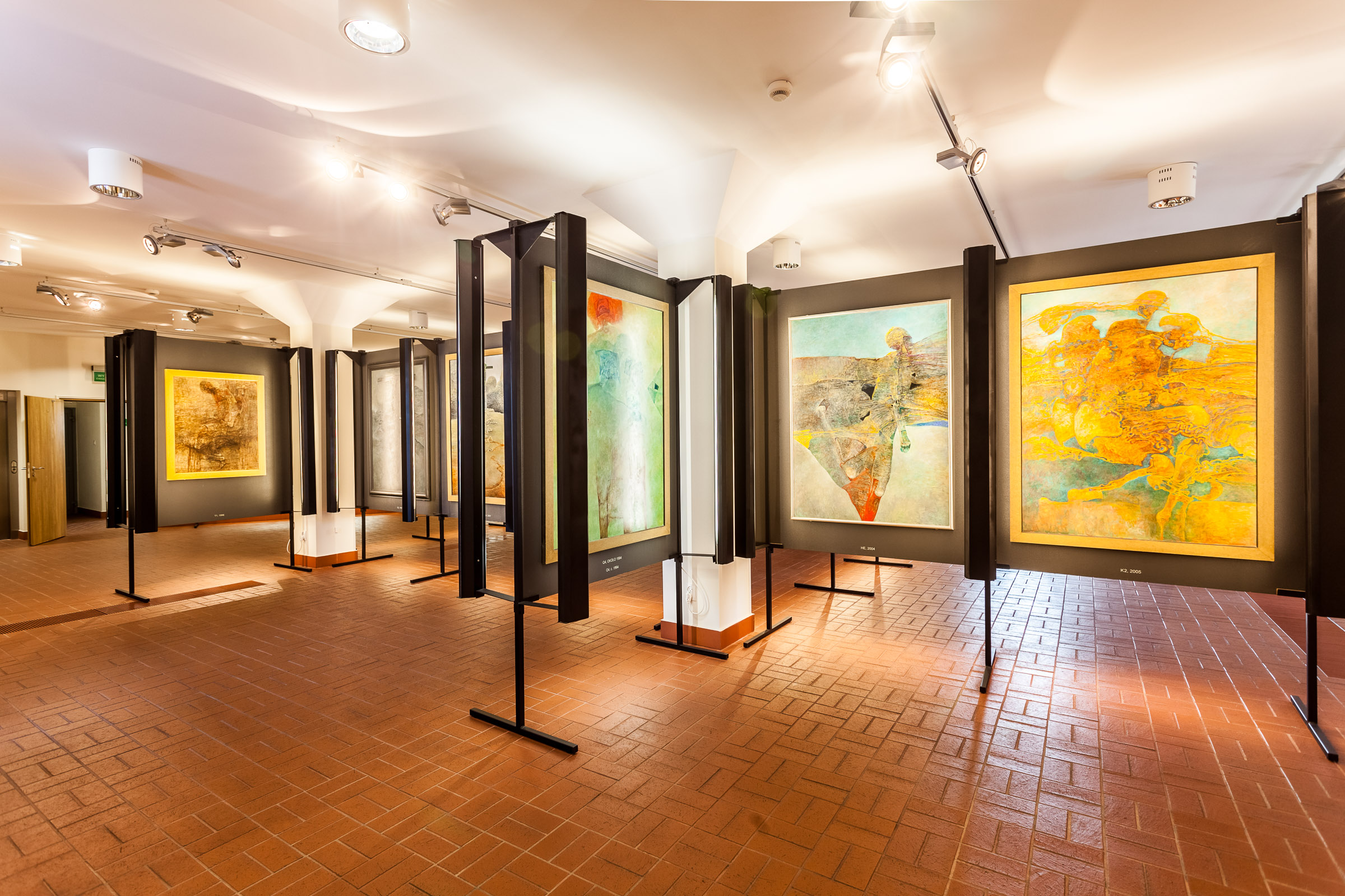 Sala wystawowa. Na ścianach zawieszone obrazy Beksińskiego. W pomieszczaniu jest jasno.