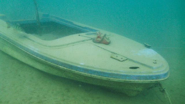 Zdjęcie pod wodą. Na dnie zatopiona łódka.
