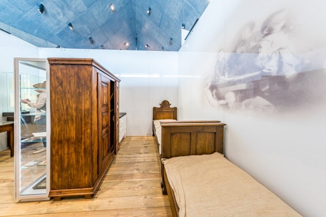 Część ekspozycji muzealnej. Dwa drewniane łóżka i strara drewniana szafa.