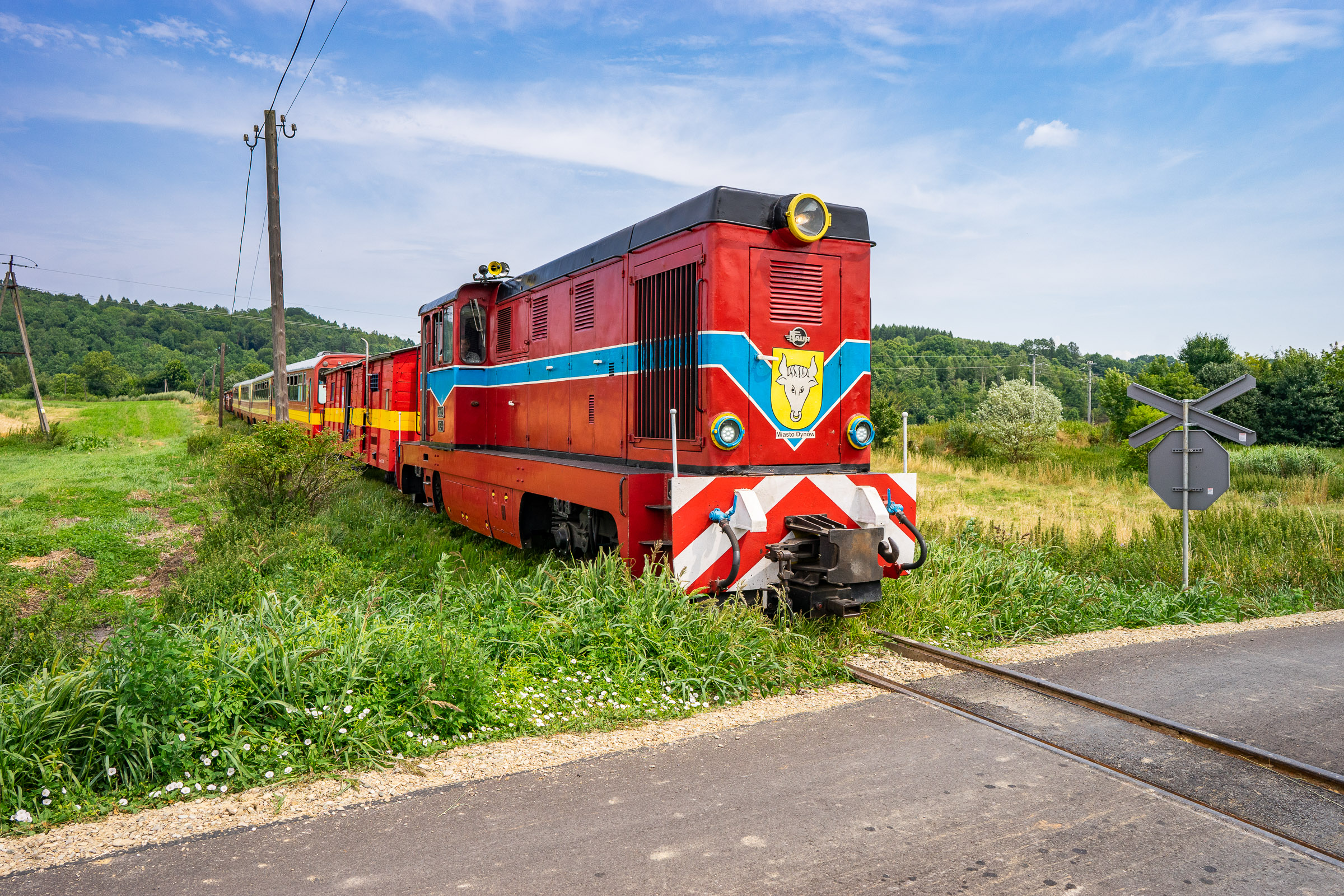 Czerwony pociąg zbliżający się do przejazdu przez drogę