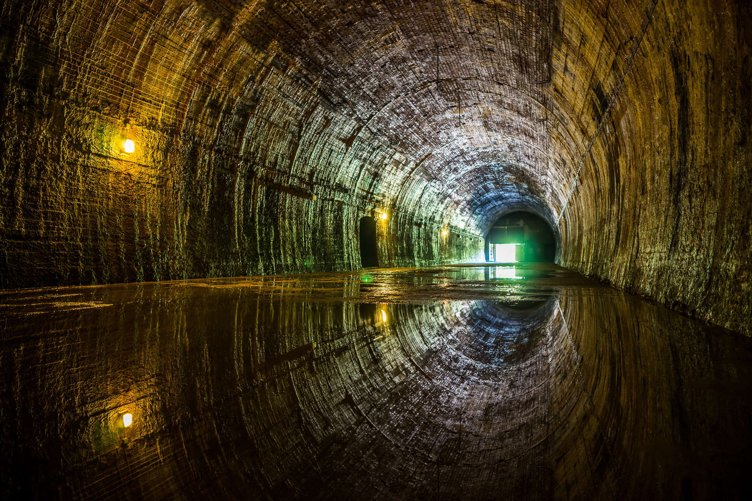 Wnętrze tunelu kolejowego. Tunel rozświetlają umieszczone co kilka metrów pojedyncze lampy.