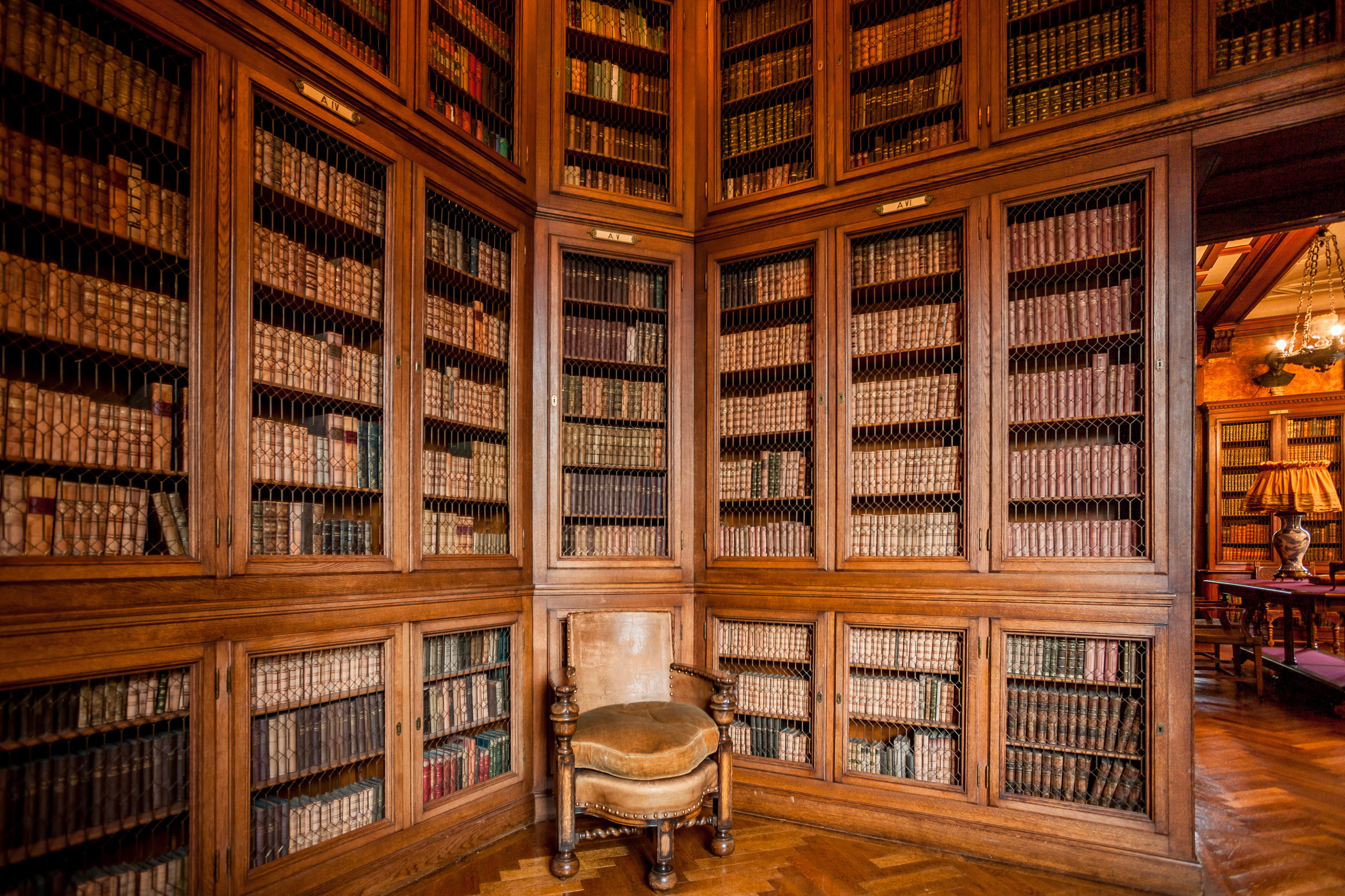 Eleganckie wnętrze w stylu angielskim. Przy ścianach drewniane, zdobione regały z książkami.