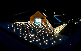Nocne zdjęcie budynku Muzeum Ulmów z lotu ptaka. Dziedziniec muzeum rozświetlony pojedyńczymi prostokątnymi światłami.