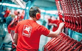 Linia produkcyjna rowerów. Na pierwszym planie mężczyzna w czerwonej koszulce z logo i napisem ROMET