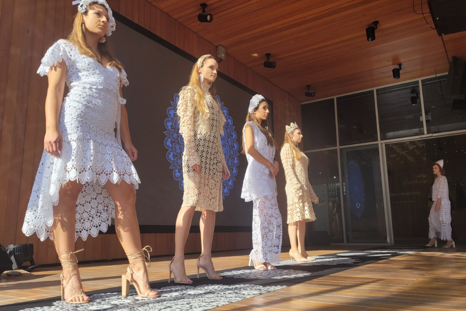 Pokaz mody. Cztery modelki prezentują sukienki z motywem koronki koniakowskiej.