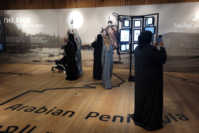 Grupa osób w arabskich strojach przygląda się elementom wystawy.