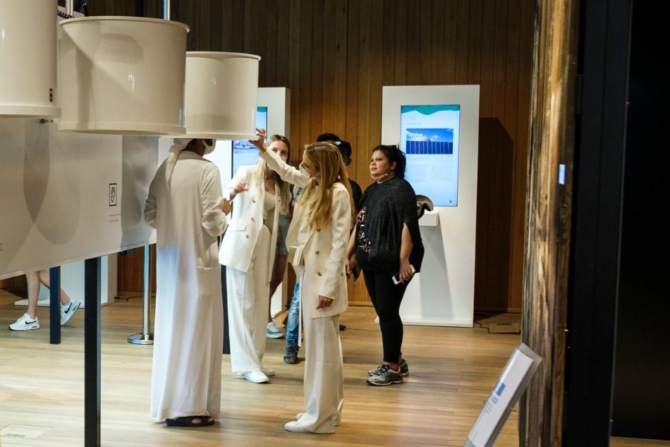 Element wystawy województwa podkarpackiego na EXPO w Dubaju. Osoba w białym, arabskim stroju słucha dźwięków ze specjalnego głośnika.