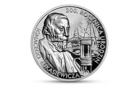 Rewers srebrenej, okrągłej monety z wizerunkiem Ignacego Łukasiewicza, prototypem lampy naftowej oraz widokiem na założoną przez Łukasiewicza najstarszą na świecie kopalnię ropy naftowej w Bóbrce.