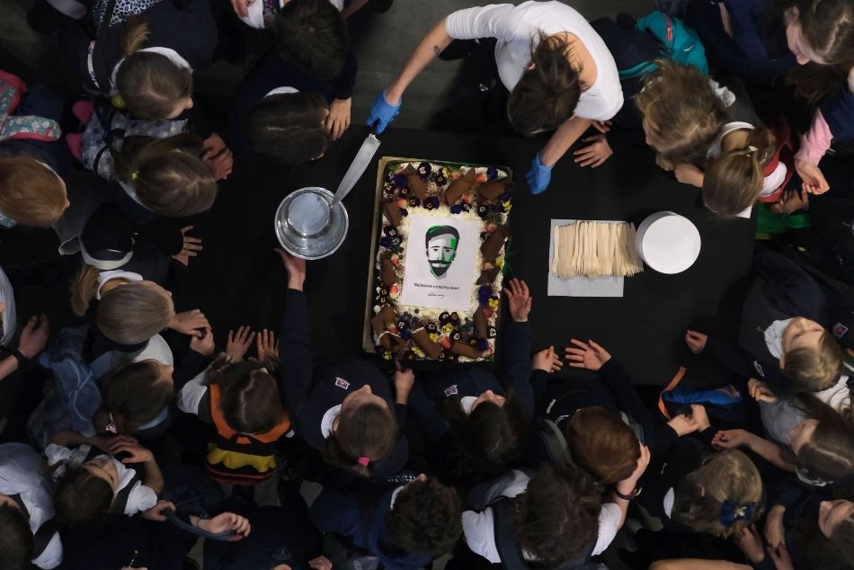 Zdjęcie z góry. Grupa dziedzi wokół tortu z wizerunkiem Ignacego Łukasiewicza.