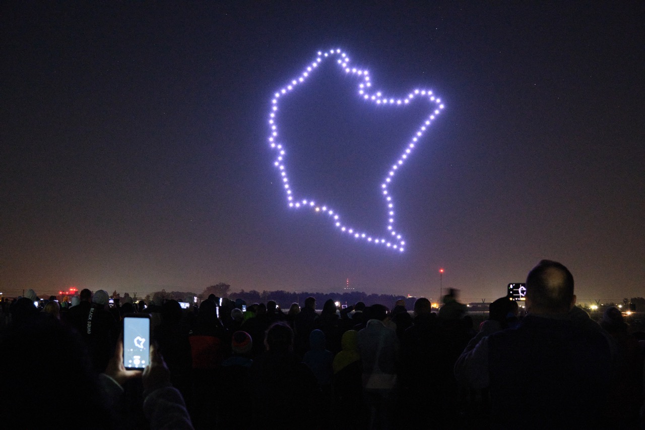 Nocny pokaz dronów. Świecące drony lecące w szyku tworzą mapę konturową województwa podkarpackiego.