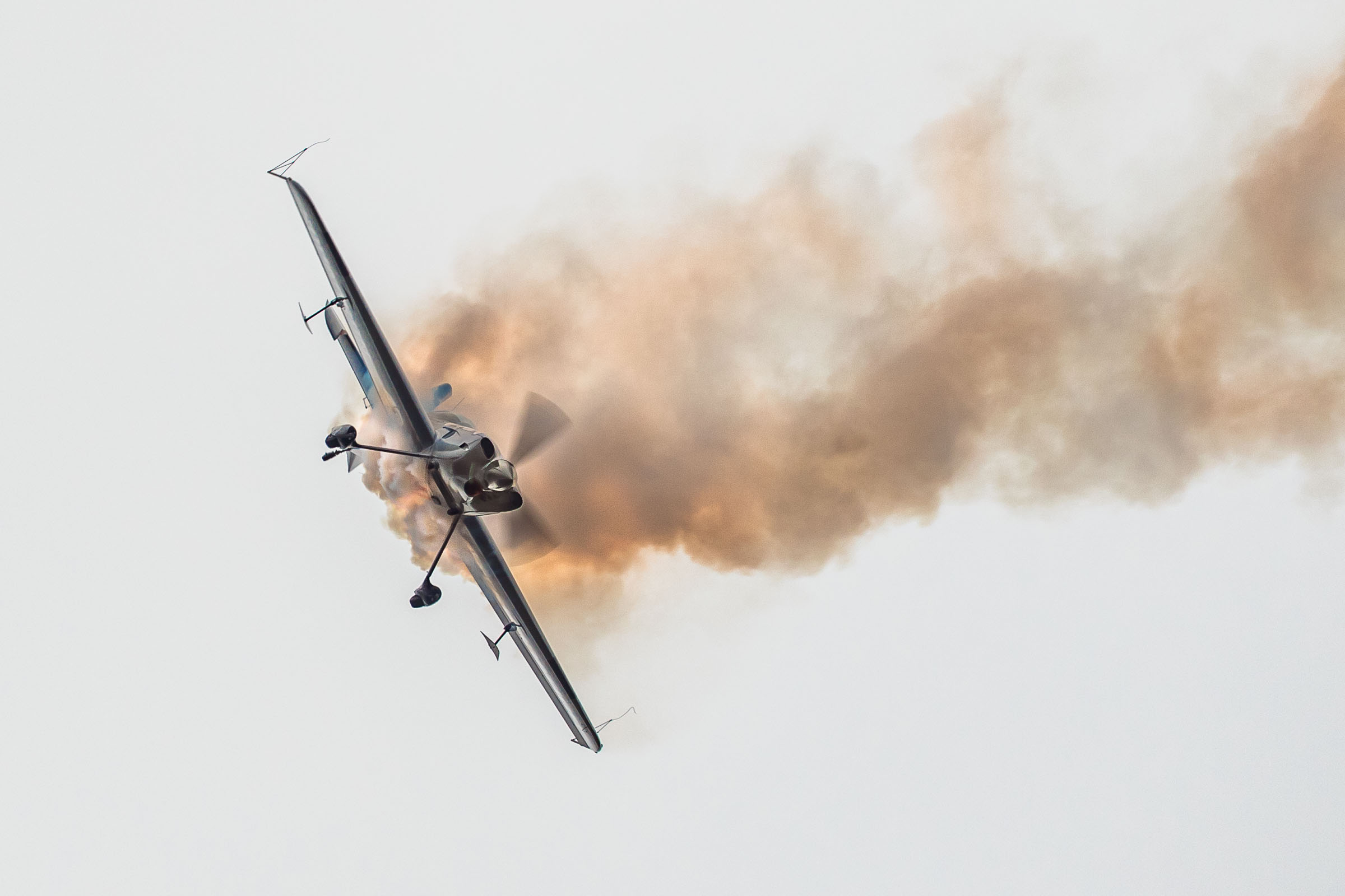 Samolot GB1 wykonujący podniebne akrobacje. Samolot wykonuje manewr skrętu, jest przechylony na bok, za samolotem ciągnie się smuga dymu.