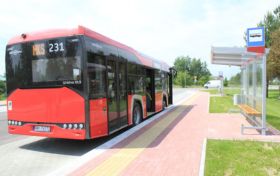 Czerwony autobus komunikacji miejskiej stojący przy przystanku.