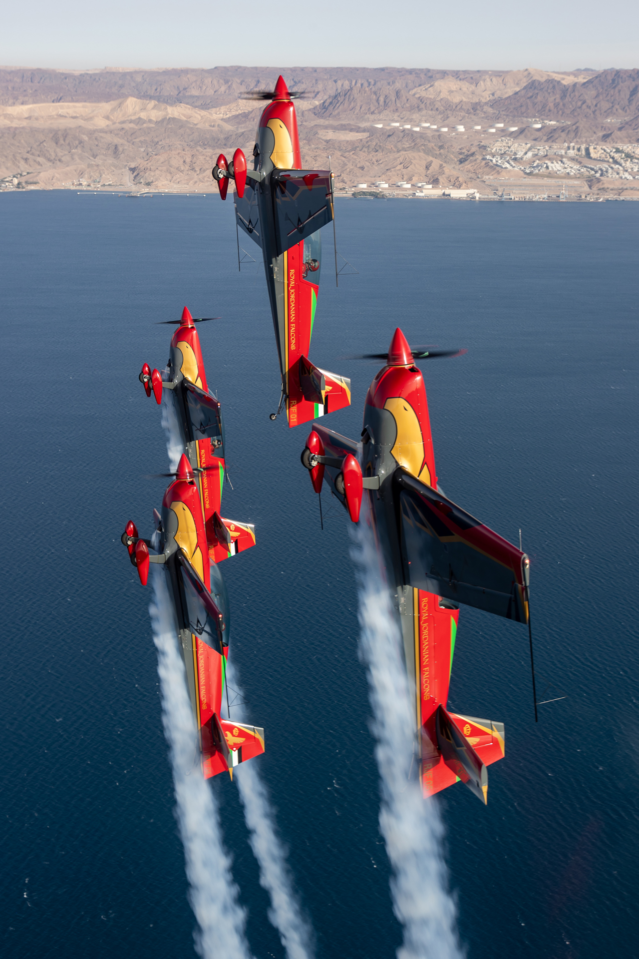 Cztery czerwone samoloty lecące pionowo w górę, w szyku w bliskiej odległości.