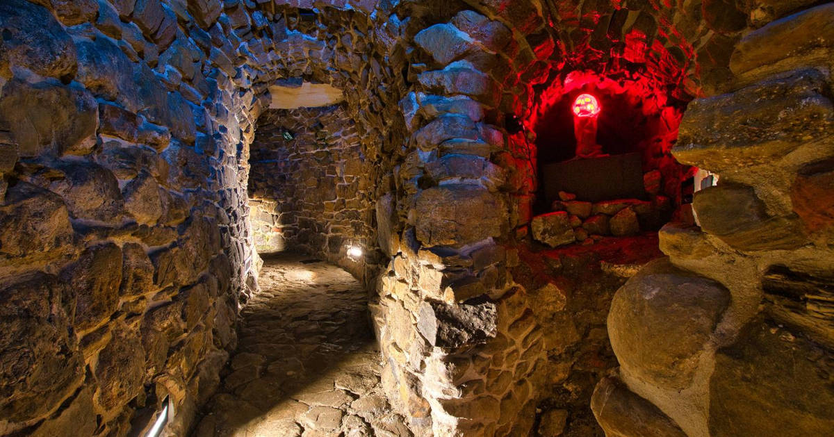 Podziemny korytarz z kamiennymi ścianami i stropem.